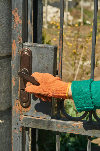 Una mano en un guante de trabajo abre una puerta de metal
 - Foto, imagen