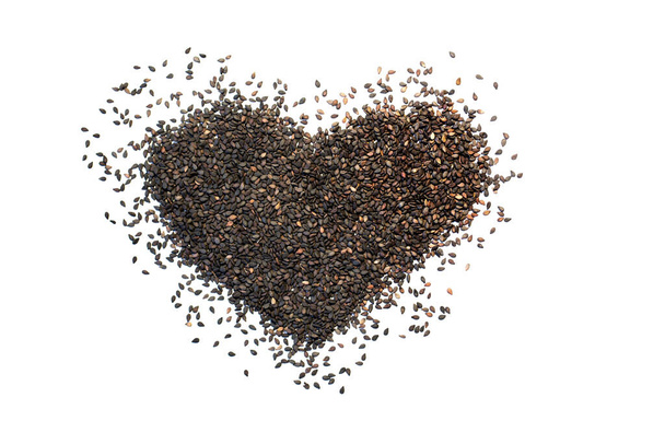 Heart shape made from black sesame seeds on a white isolated background. Flat lay. - Foto, Imagem