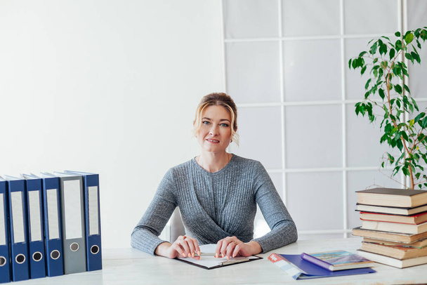 retrato de una mujer de negocios en una mesa con libros y documentos en el trabajo en la oficina
 - Foto, imagen