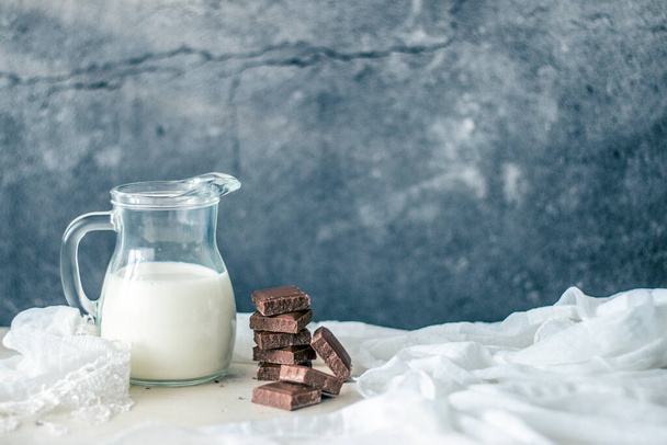 Photo of bottle of milk and chocolate on rustic table and grundge background - 写真・画像