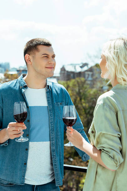 smiling couple with red wine on sunny terrace - Foto, afbeelding
