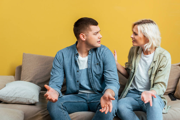 Junges Paar streitet auf Sofa nahe gelber Wand - Foto, Bild
