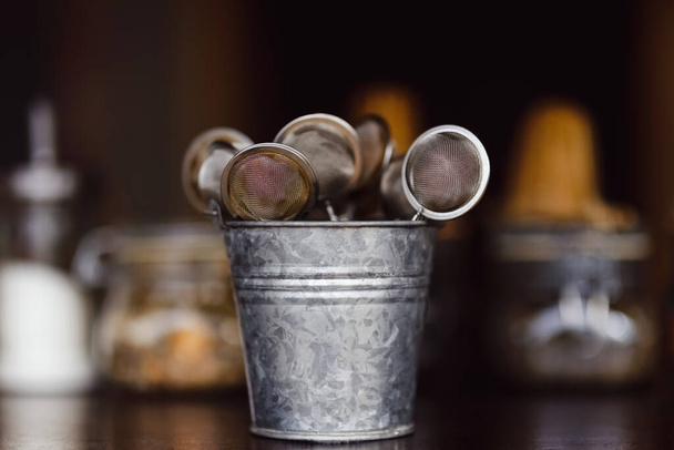 Tea strainers in a zinc bucket on a bar counter - 写真・画像