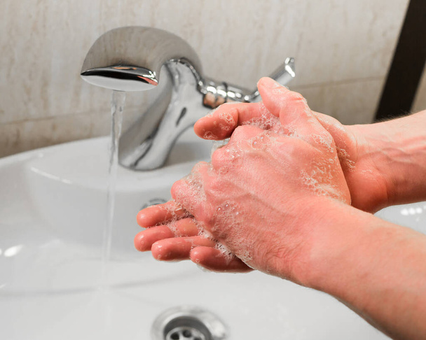 Mann wäscht sich im Badezimmer die Hände mit Wasser und Seife - Foto, Bild
