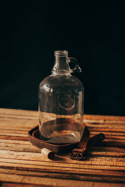 Escenario de madera vintage, jarrón de vidrio, metales oxidados, cuero viejo y herramientas oxidadas sobre un fondo negro
 - Foto, Imagen