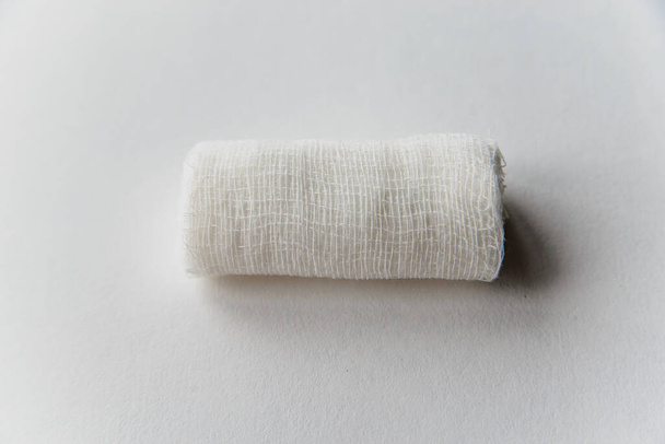 a roll of white bandage lies on a white surface - Foto, afbeelding