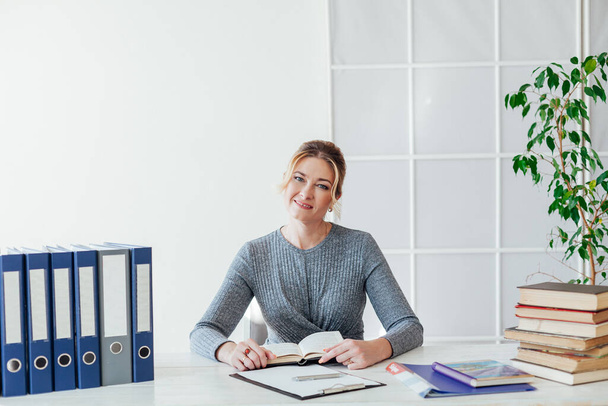 portret bizneswoman przy stole z książkami i dokumentami w pracy w biurze - Zdjęcie, obraz