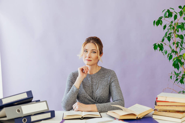 portrait of a businesswoman at a table with books and documents at work in the office - Fotoğraf, Görsel