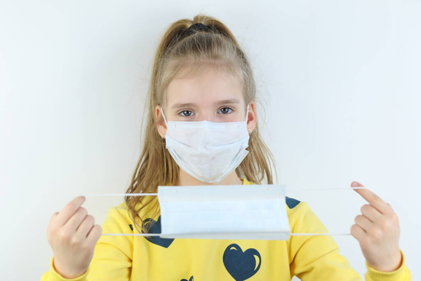 Glad and happy beautiful joy,child in the medical helthcare guarding or protecting mask and in yellow t-shirt on the white background for easy extraction offering to take another mask - 写真・画像