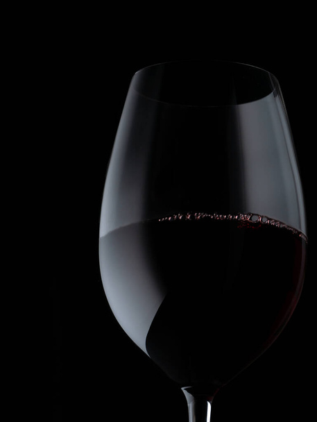 Glassed of red wine isolated on black background. Elegant red wine glass and a wine bottle. Bottle silhouette - Photo, image