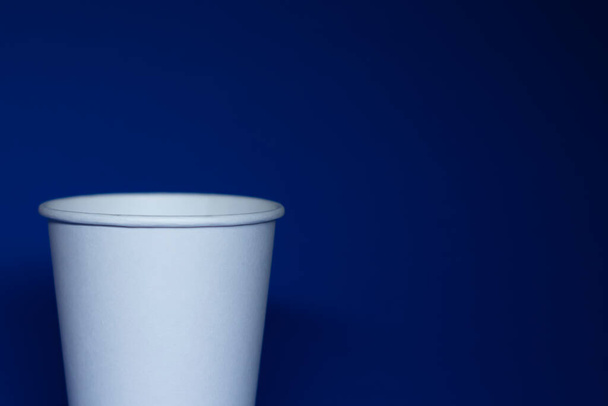 An empty white paper cup on a blue background - Photo, Image