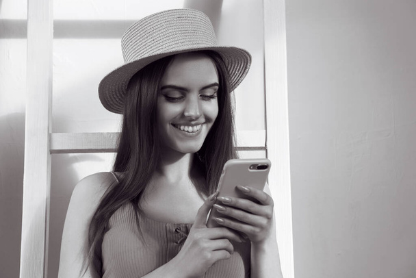 Black and white portrait of young Girl using smartphone and smiling with copy space - Photo, Image