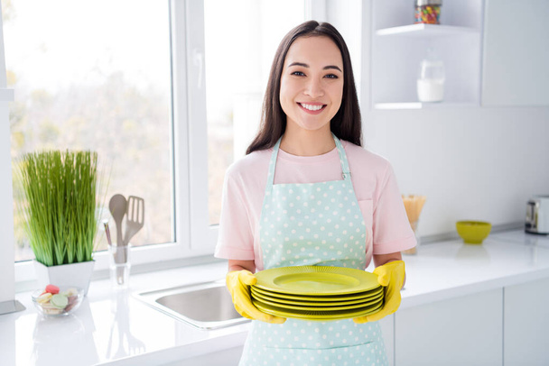 Portrait of her she nice attractive lovely cheerful cheery hardworking brunet girl making fast domestic work holding in hands clean plates in modern light white interior kitchen indoors - Foto, Imagem