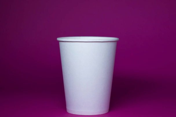 Una taza de papel blanco vacía sobre un fondo rosa
 - Foto, Imagen