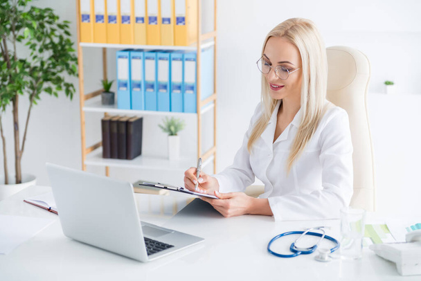 Portrait of her she nice attractive cheerful focused experienced girl doc experienced therapist physician writing sickness history meds cure remedy advice in modern light white workplace workstation - Fotografie, Obrázek