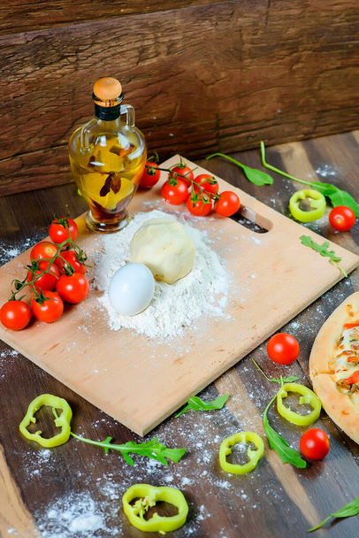 italian pizza, with ingredients, flour, eggs, peppers, tomatoes, dough, greens, home made. - Fotografie, Obrázek