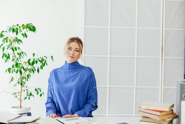 портрет деловой женщины за столом с книгами и документами на работе в офисе
 - Фото, изображение