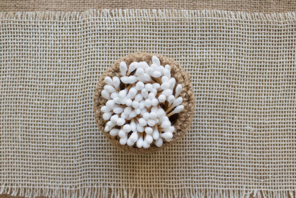Vista superior em paus de algodão de bambu em cesta de malha artesanal em renda natural e fundo de tecido. Espaço de cópia, eco amigável e zero conceito de resíduos
 - Foto, Imagem