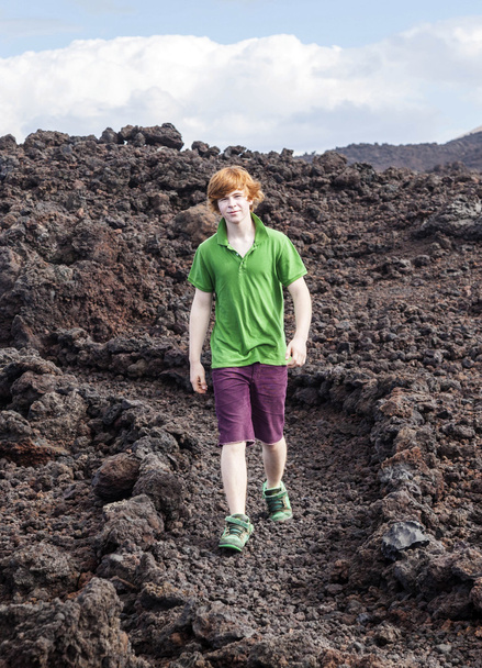 Poika kävelee vulkaanisella alueella
 - Valokuva, kuva