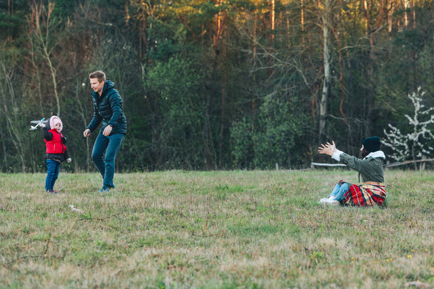 jovem família feliz de três brincando ao ar livre no ar fresco com brinquedo liso. Hora da primavera. actividades de lazer
 - Foto, Imagem