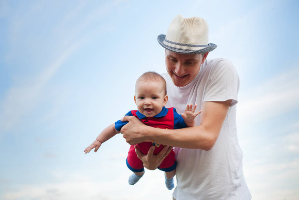 Kleines Baby im Arm des Vaters vor blauem Himmel, Vatertag, Vaterschaft, glückliches Baby - Foto, Bild