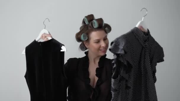 Young woman in curlers on hair and lingerie choosing dress to wear from wardrobe - Footage, Video