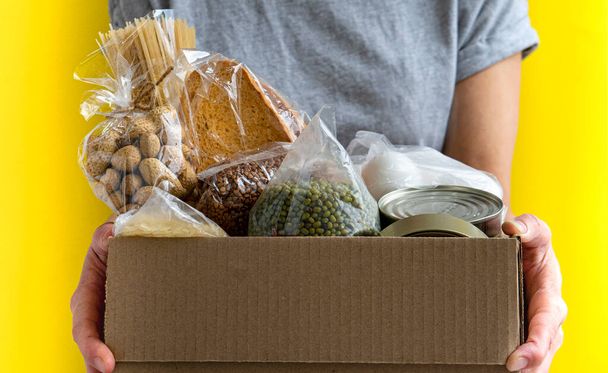 Il volontario tiene la scatola delle donazioni con il cibo per le persone bisognose
 - Foto, immagini