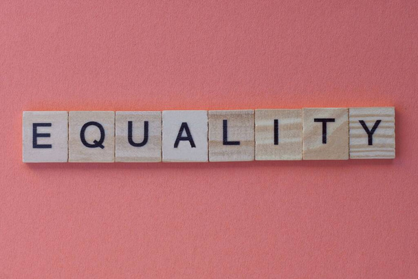 Слово равенство из серых деревянных букв лежит на красном фоне
 - Фото, изображение