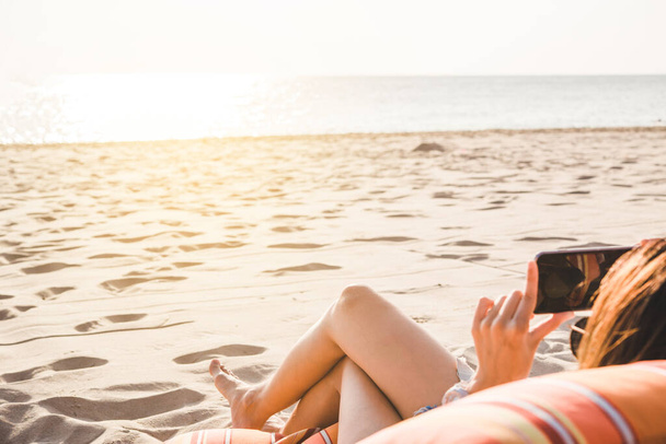 Mooie jonge vrouw benen rusten en ontspannen op het strand. Se - Foto, afbeelding
