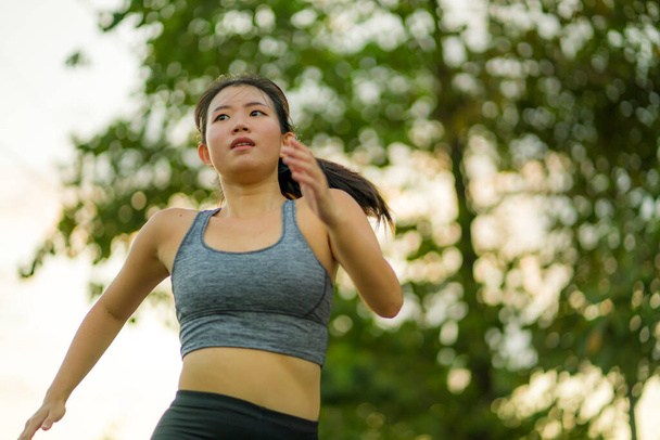 outdoors running workout - young happy and dedicated Asian Korean woman jogging at beautiful city park or countryside trail on sunset enjoying fitness and cardio activity in healthy lifestyle - Fotoğraf, Görsel