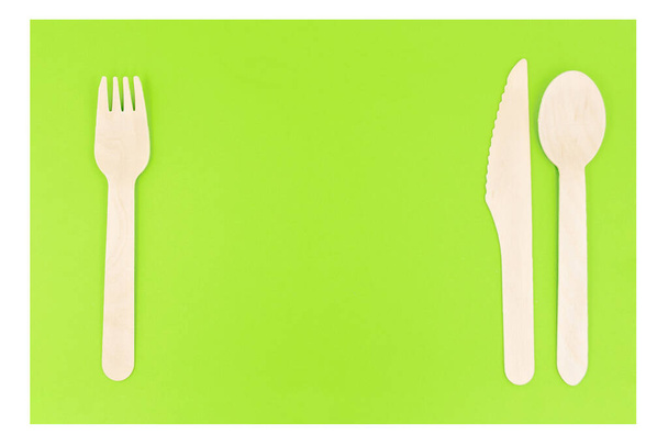 Eco friendly disposable cutlery utensils on green background. Bamboo wooden fork, knife and spoon. Zero waste concept - Photo, Image