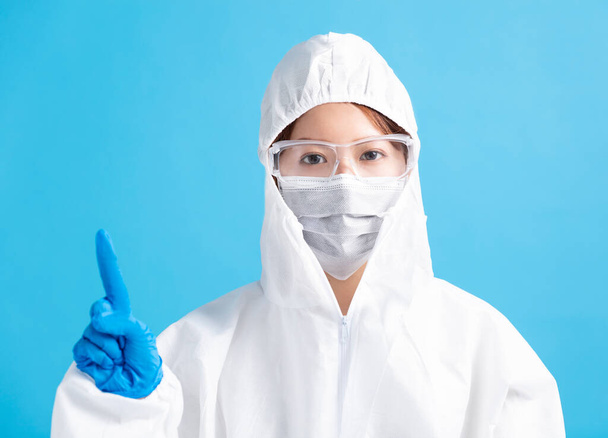 γυναικεία νοσοκόμα που φοράει ιατρική μάσκα με γυαλιά ασφαλείας και με λευκή προστατευτική στολή. - Φωτογραφία, εικόνα