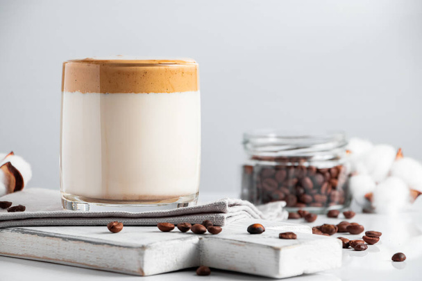 韓国の飲み物のトレンド- dalgonaコーヒー。軽い背景に甘いホイップフォームを持つアイスミルクのガラス。テキストの場所 - 写真・画像