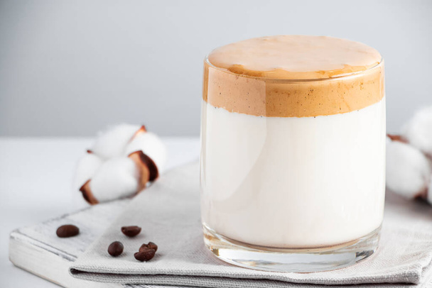 Παγωμένος καφές νταλγκόνα. Ένα ποτήρι μοδάτο αφράτο ποτό φτιαγμένο από γάλα και σαντιγί σε γκρι φόντο. Θέση για κείμενο - Φωτογραφία, εικόνα