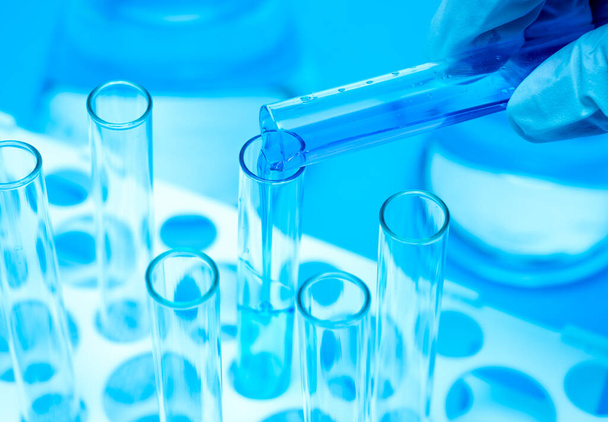 A researchers hand holding a test tube containing blue liquid. - Fotoğraf, Görsel