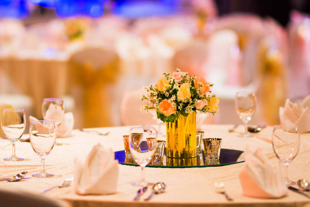 rózsa virágárus üveg váza dekoráció vacsoraasztalon evőeszközök és gyertya indiai esküvői beállítás beltéri dekoratív fények és gyönyörű bokeh. - Fotó, kép