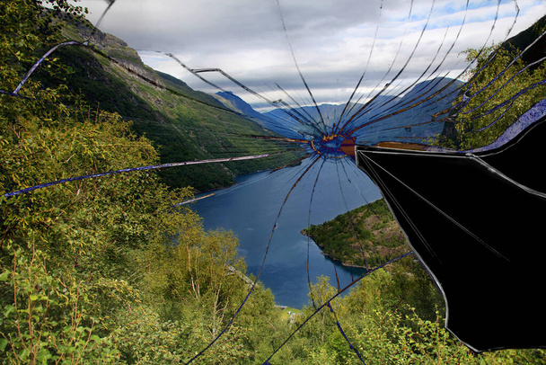 broken mirror with cracks - the concept of a failed vacation, canceled trip, spoiled vacation, disaster, quarantine, isolation. beautiful scandinavian fjord with blue water - Фото, изображение
