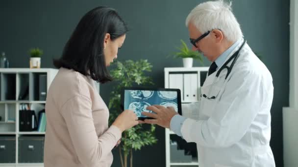 Zieke vrouw die MRI-beelden bekijkt op tabletscherm tijdens een doktersafspraak in de kliniek - Video