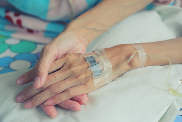 Εραστές που κρατούν τα χέρια των ασθενών με πυρετό έχουν IV σωλήνα. - Φωτογραφία, εικόνα