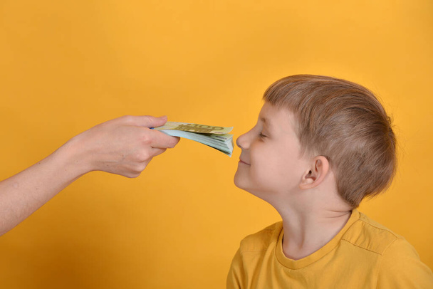Un garçon avide renifle l'argent avec toute sa cupidité
. - Photo, image