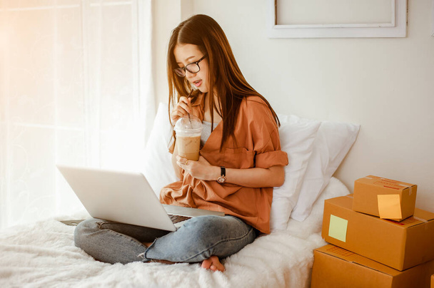 Young woman asian work from home talking with customers to sell products online and delivery for customer. Business owner, SME, shipping, work from home(WFH), freelance, Start up concept. - 写真・画像