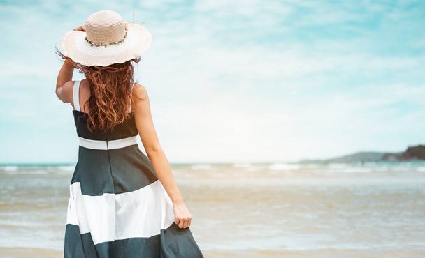 Happy asian women with holding hat stand to receive the wind and enjoy life on the beach vacation. beach, summer, liftstyle, positive mood, travel, relax concept. - Φωτογραφία, εικόνα
