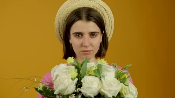 Μπροστά όψη της ελκυστική κοπέλα στο καπέλο κρατώντας λουλούδια με χαμόγελο - Πλάνα, βίντεο