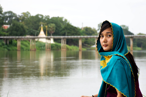 Reizigers thai vrouwen alleen dragen kleding mon etnische stijl voor het nemen van foto eenzaam aan de rivieroever van Mae Khlong of Meklong rivier bij Ban Pong in de avond in Ratchaburi, Thailand - Foto, afbeelding