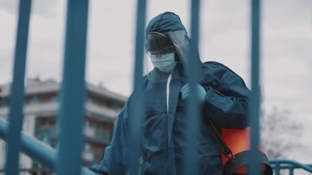 A person wearing a blue protective suit disinfecting public space - Séquence, vidéo