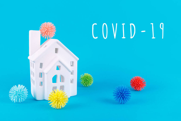 Carino casetta e palline di plastica come virus su blu con formulazione COVID-19. Epidemia, isolamento sociale, coronavirus COVID-19 concept
 - Foto, immagini