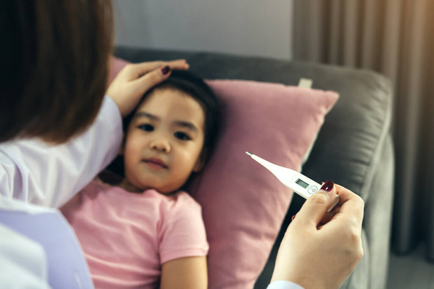 Pediatra asiática está usando um termômetro para medir a febre para crianças
 - Foto, Imagem