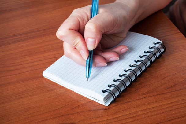 Hand write on notebook. Close up. Wooden table - Φωτογραφία, εικόνα