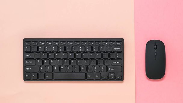 Drahtlose Tastatur auf rosa Hintergrund und drahtlose Maus auf rotem Hintergrund. - Foto, Bild
