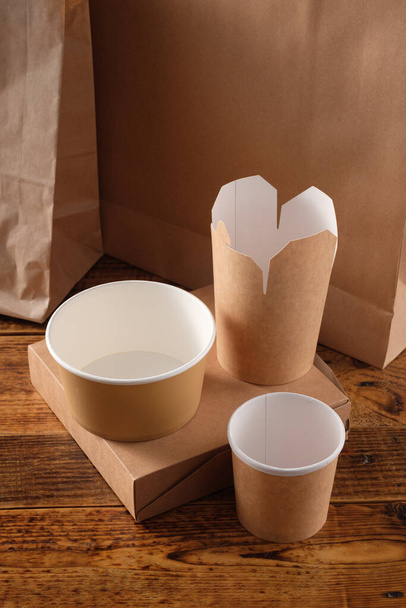 Street fast food paper cups, plates and containers. Eco-friendly food packaging on wooden background. Copy space. Carering of nature and recycling concept. - 写真・画像
